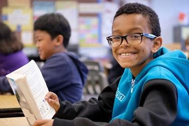 A student holds a book and smiles for a photo